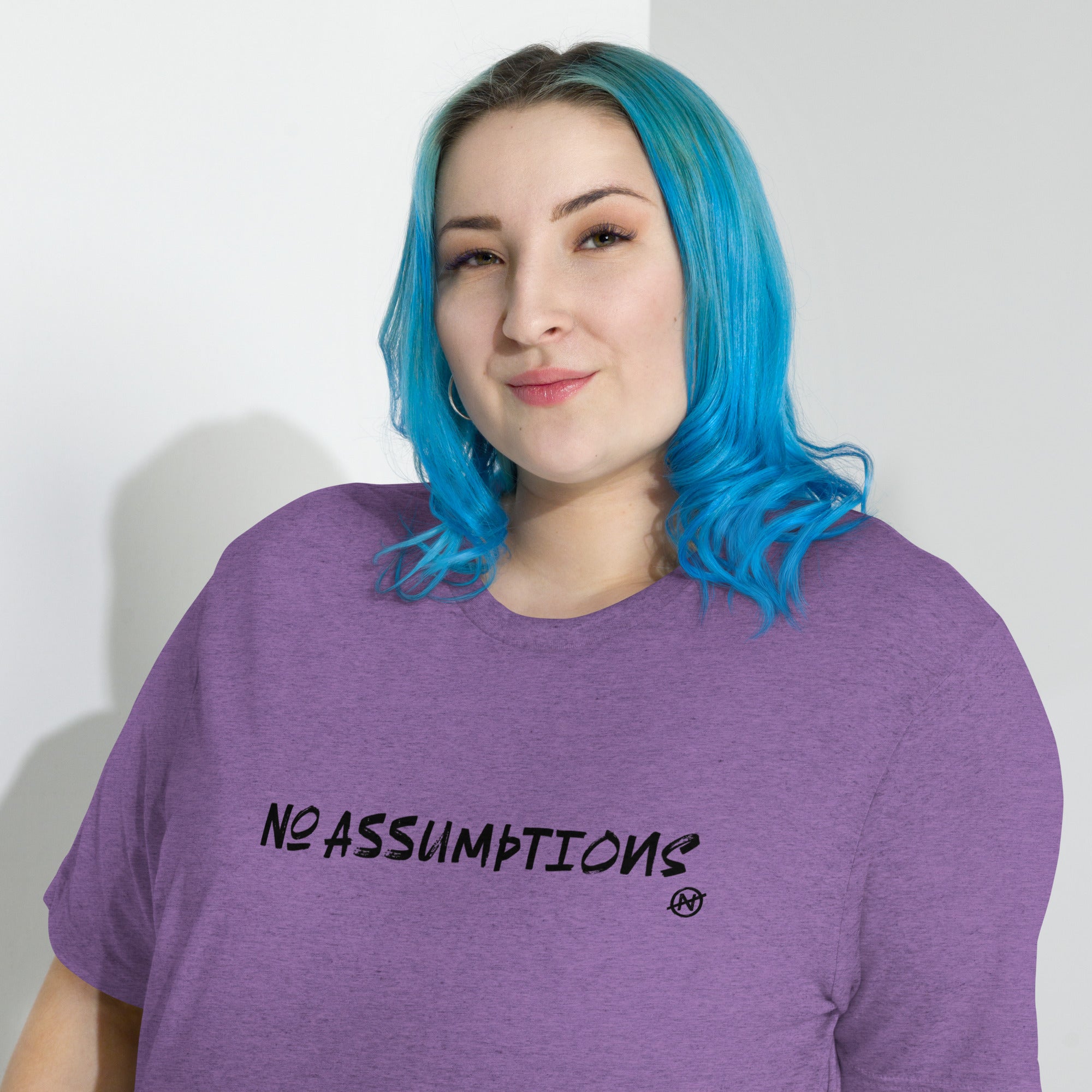Person wearing a purple t-shirt with 'NO ASSUMPTIONS' text on a plain background